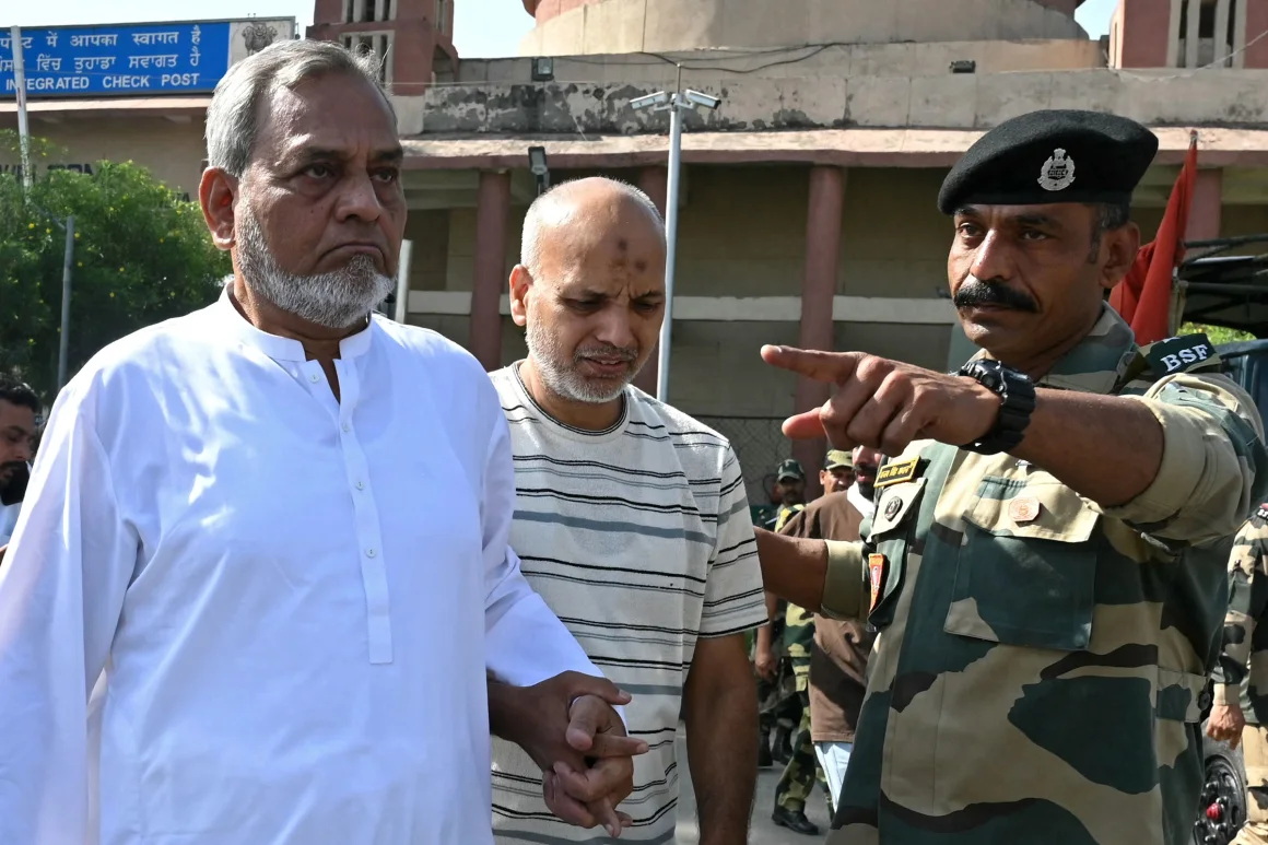 印度边境安全部队士兵向通过印巴瓦格赫边境哨所返回巴基斯坦的巴基斯坦公民示意 ...