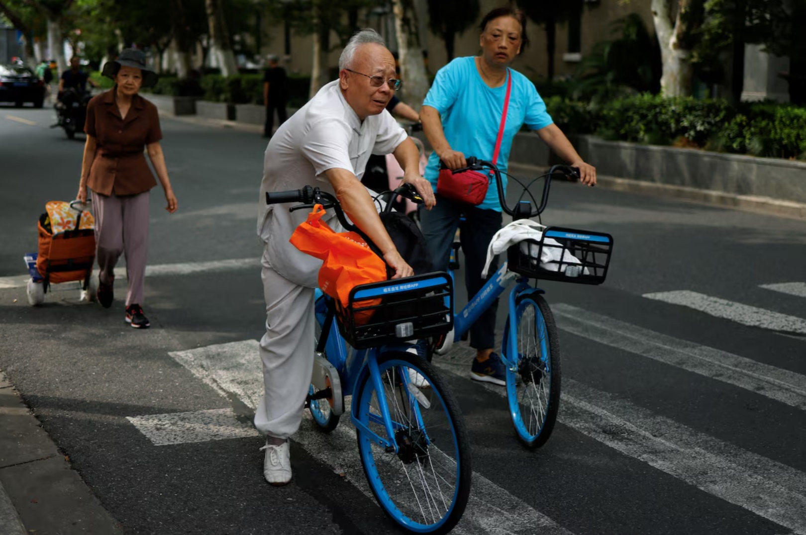 中国上海，老年人在街道上骑着共享单车